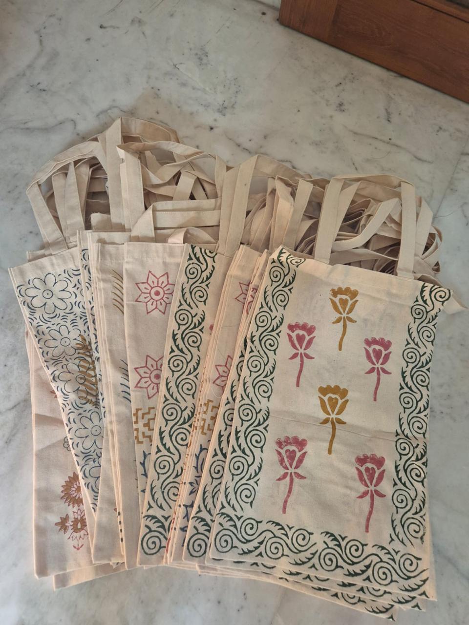 Stack of hand block-printed cotton tote bags in assorted designs