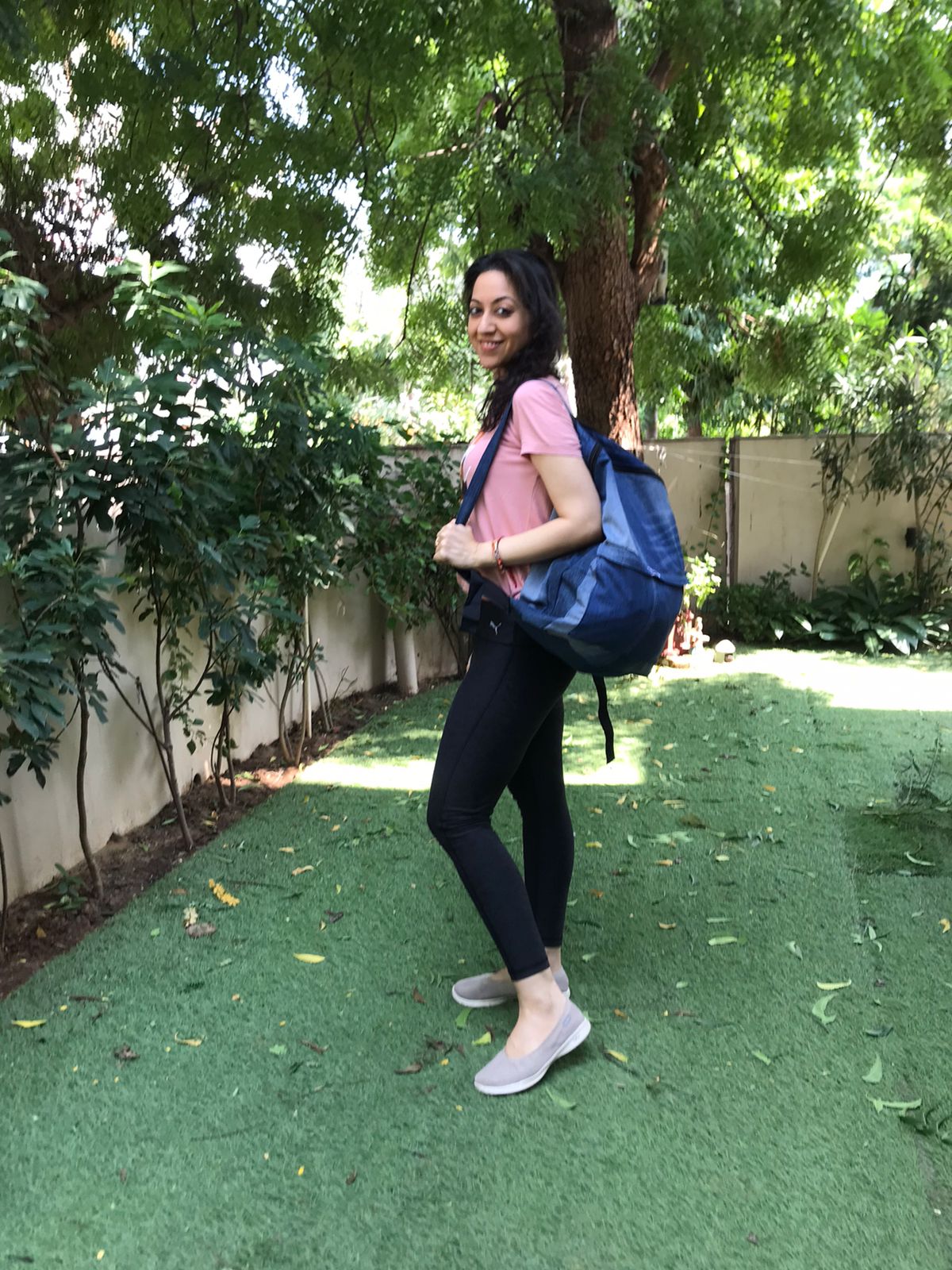 Customer carrying a large denim duffle bag over her shoulder in a garden